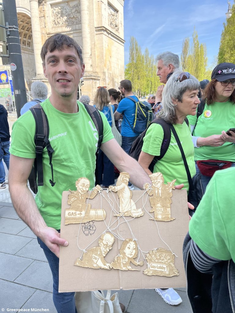 Greenpeace München mit karikaturistischem Schild bei der Demo für erneuerbare Energien.